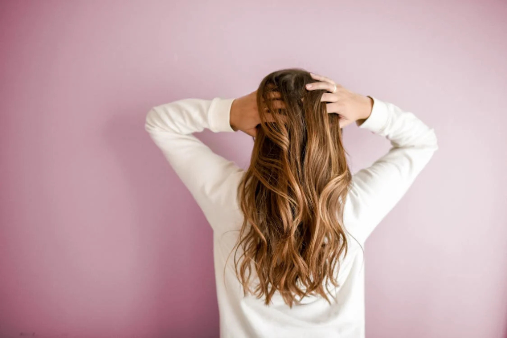 Woman with healthy, voluminous red hair turned around after hair restoration treatment