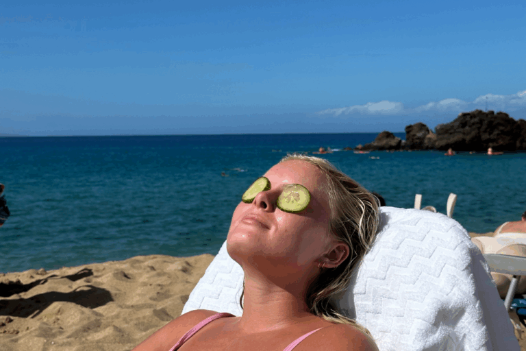 Woman relaxing on a beach with cucumbers on her eyes, highlighting the need for sun protection to prevent skin cancer