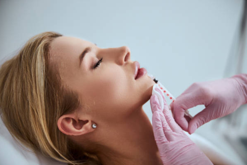 Close-up of a patient receiving dermal fillers to enhance her lips and jawline at a medical spa.